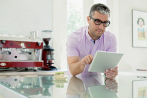 Portrait of man using digital tablet in domestic kitchen